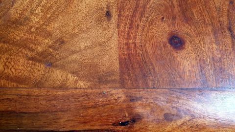 Ein Holzmöbelstück zeigt eine Fläche mit Wasserflecken, die durch Anwendung von Walnussöl aufgefrischt wurde.