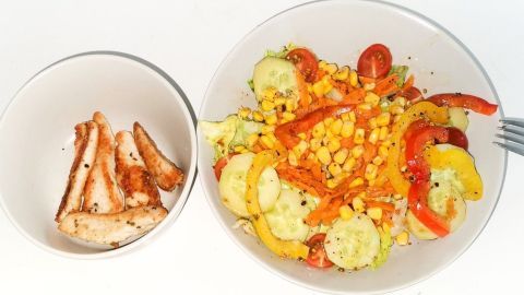 Ein bunter Salat mit frischen Gemüsesorten wird mit knusprigen Putenstreifen serviert, perfekt für eine gesunde Mahlzeit.