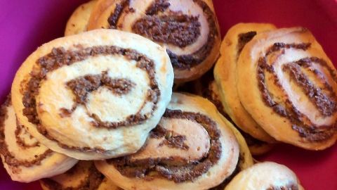 In einer pinken Schüssel liegen Nussschnecken, die appetitlich spiralförmig geformt sind und gebacken wurden.