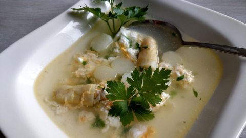 Eine cremige Spargelsuppe mit Spargelresten, garniert mit frischer Petersilie, auf einem weißen Teller präsentiert.