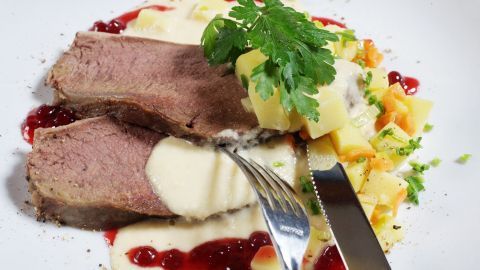 Zarte Semerrolle liegt auf einem Teller, garniert mit Meerrettichsoße, umgeben von buntem Gemüse und einer Sauce.