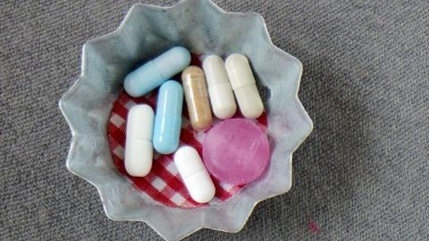 In einer Schale liegen verschiedene große Tabletten und Kapseln, umgeben von einem rot-weißen Tuch.