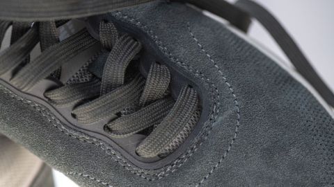 Wildlederschuhe liegen im Fokus, während ein Mikrofasertuch zum Reinigen und Aufrauen verwendet wird.