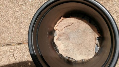Ein Blumentopf mit einem alten Feinstrumpfhosenstück dient als Praktikabilität, um Pflanzen richtig zu bewässern.