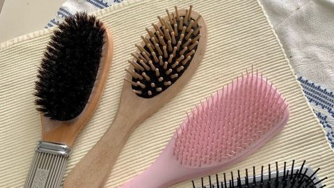 Haarbürsten liegen auf einem hellen Untergrund und sind bereit zur Reinigung mit Spülmittel und Backpulver.