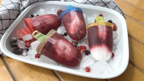 Eine bunte Auswahl an selbstgemachtem Wassereis liegt auf Eis und frischen Beeren in einer modernen Umgebung.
