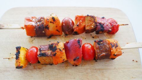 Bunte Grillspieße mit Tofu und Nektarinen liegen auf einem Holzbrett, bereit zum Servieren und Genießen.