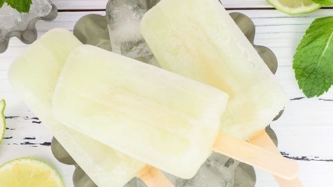 Eis am Stiel, erfrischend und gesund, liegt auf Eis in einer Schale, umgeben von Limettenscheiben und Minzblättern.