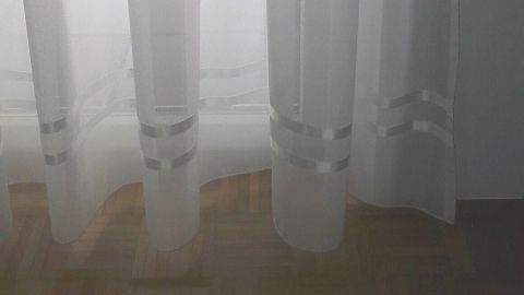 Ein transparenter Vorhang hängt und bietet Blick auf einen hellen Raum, in dem ein Tisch und Stühle stehen.