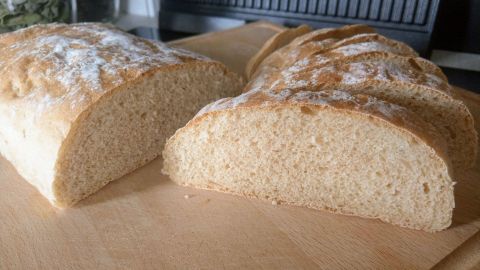 Das frisch gebackene Dinkel-Ciabatta liegt auf einem Holzbrett, in dünne Scheiben geschnitten, mit einer goldenen Kruste.