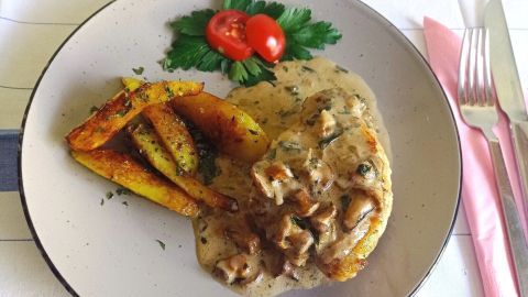 Zartes Jägerkrüstchen in cremiger Sauce, begleitet von knusprigen, gebackenen Kartoffelspalten und frischen Tomaten.