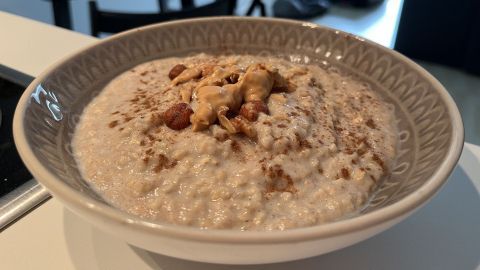 Ein Bananen-Porridge liegt in einem hübschen Schüssel, garniert mit Nüssen und Erdnussbutter, im modernen Küchenumfeld.