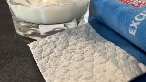 Ein Glas mit heller, cremiger Substanz steht auf einer dunklen Oberfläche, neben einem weichen Tuch zur Linderung von Juckreiz.