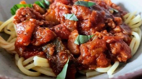 Eine warme Portion Spaghetti mit einer reichhaltigen Salsiccia Bolognese-Sauce und frischen Kräutern, serviert in einer Schüssel.