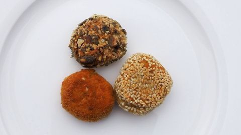 Drei verschiedene Falafel aus Kichererbsenmehl liegen schön auf einem weißen Teller in frischen Farben.