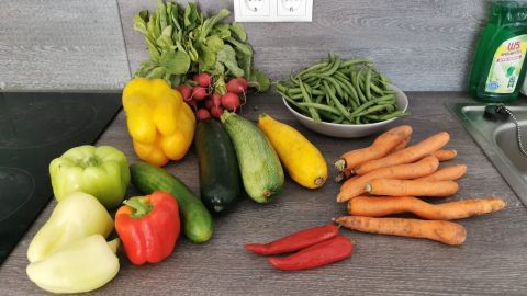 Bunte frische Lebensmittel wie Paprika, Zucchini und Karotten liegen auf einem Tisch, bereit zum Kochen in einer modernen Küche.