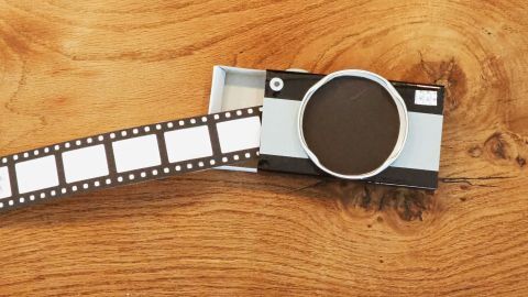 Eine Kamera-Verpackung liegt auf einem Tisch, während ein Filmrollenteil herausgezogen wird und kreative Ideen anregt.