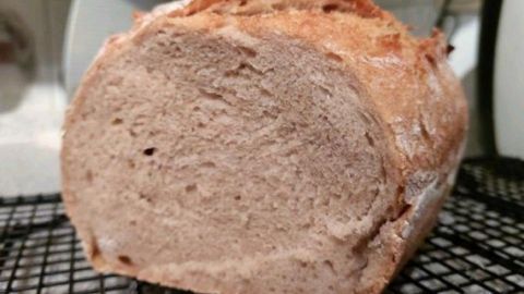 Ein frisch gebackenes Brot mit knuspriger Kruste liegt auf einem Gitter, bereit zum Servieren.
