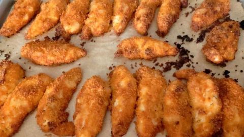 Knusprige Hähnchensticks liegen auf Backpapier, frisch zubereitet und golden gebacken, bereit zum Servieren.