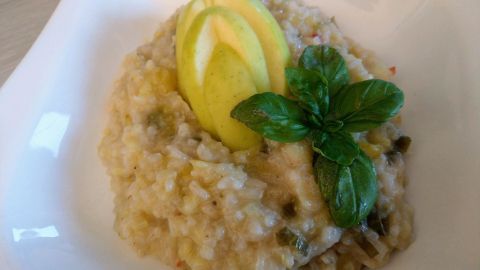Cremiges Apfelrisotto wird in einer weißen Schale serviert, garniert mit Apfelscheiben und frischem Basilikum.