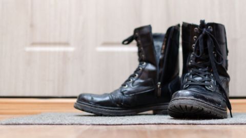 Schwarze Stiefel stehen auf einer Matte im Flur, bereit, mit Nagellack kleine Kratzer auszubessern.