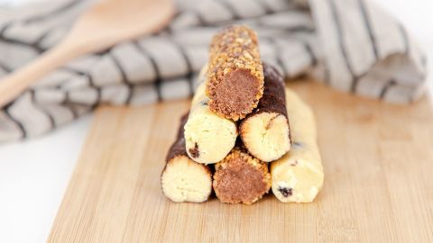 Leckere Plätzchen von der Rolle stehen gestapelt auf einem Holzbrett, umgeben von einem gestreiften Küchentuch.