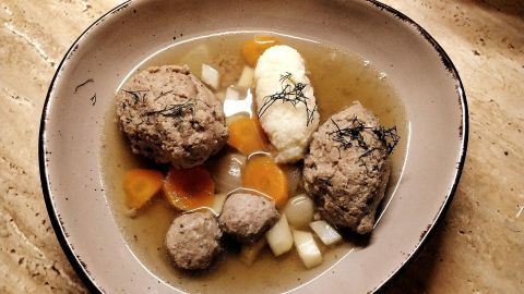 Eine gefüllte Schüssel mit Rinderkraftbrühe zeigt große Fleischklöße, Gemüse und Einlagen in einer klaren Brühe.