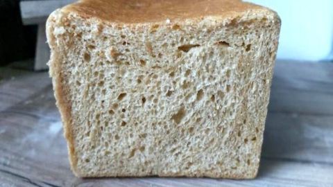 Frisches Toastbrot mit Sauerteig steht auf einem Holztisch, umgeben von einer gemütlichen Küchenszene.