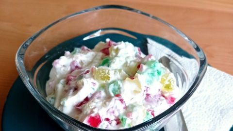 Eine Schüssel mit buntem Konfetti-Quark steht auf einem Teller, umgeben von einer servierbereiten Tischumgebung.
