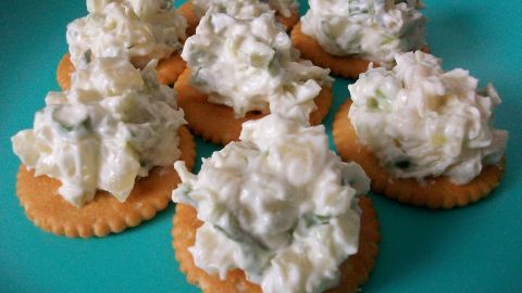 Kekse sind mit einer cremigen Ananas-Philadelphia-Mischung belegt und auf einem blauen Teller angerichtet.