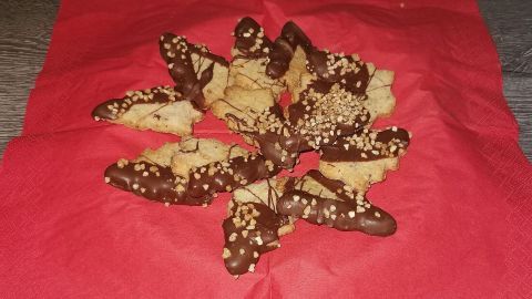 Tannenbaum-Plätzchen aus Keksen, dekoriert mit Schokolade und Nüssen, liegen auf einer roten Serviette.