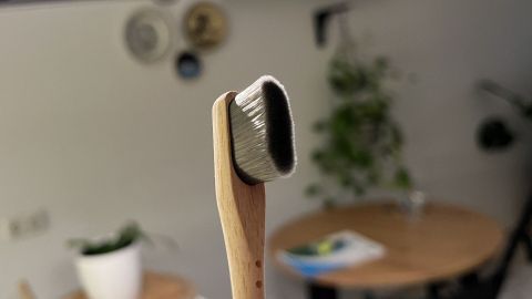 Eine Nano-Zahnbürste steht im Vordergrund, während sie in einer modernen Küche auf einem Tisch abgestellt ist.