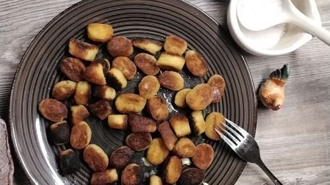 Auf einem braunen Teller liegen gebratene Huasaknäpf, daneben ein Kartoffel und eine Schüssel mit Salz. Ein Fork liegt bereit.