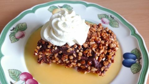 Eine schokoladeneis-schnitte liegt auf einem dekorativen Teller, umgeben von einer fruchtigen Sauce und gekrönt mit Sahne.