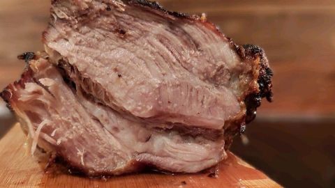 Saftiger Schweinenacken-Braten auf einem Holzbrett, perfekt gegart und goldbraun, im Hintergrund unscharfes Ambiente.