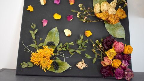 Ein schwarzes Bild zeigt getrocknete Blumen und Blätter, die kreativ angeordnet sind, um einen dekorativen Effekt zu erzielen.