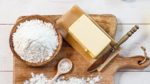 Ein Holzbrett zeigt Mehl und einen Block Butter, während ein Löffel vorbereitet wird, um Soßen mit Mehlbutter zu binden.