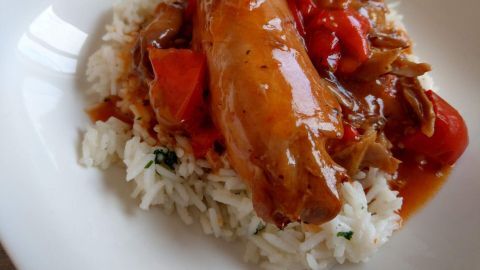 Ein saftiges Kaninchenstück liegt auf einem Bett aus Reis, umgeben von buntem, würzigem Gemüse in einer aromatischen Sauce.