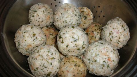 Runde Knödel aus einer Mischung von Speck und Kräutern liegen in einem Sieb und warten darauf, serviert zu werden.