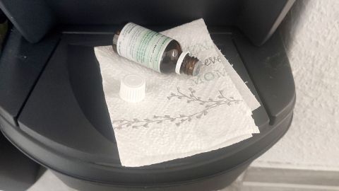Ein braunes Fläschchen liegt auf einem Stück Küchenpapier in einem Mülleimer, umgeben von einem hellen Boden und einer Wand.