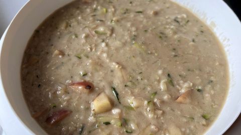 Ein cremiges Zucchini-Apfel-Porridge ohne Zucker in einer weißen Schüssel, ideal für ein gesundes Frühstück.