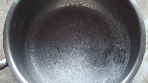 Ein Edelstahltopf zeigt eine glatte, feuchte Oberfläche, der für das Einkochen von Milch vorbereitet ist.