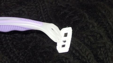 Ein Lint-Shaver entfernt Fussel von einem schwarzen, gestrickten Kleidungsstück, um es wieder sauber und gepflegt zu machen.