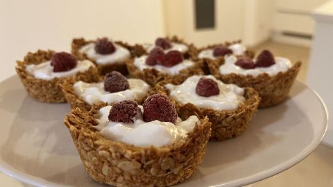 Cremige Haferflocken-Joghurt-Cups mit frischen Beeren sind auf einem weißen Teller in einer hellen Küche arrangiert.