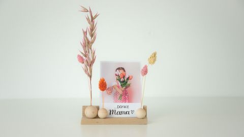 Ein Holz-Kartenhalter präsentiert ein Foto eines Mädchens mit Blumen und der Aufschrift „Danke Mama ♥“ in einem hellen Raum.
