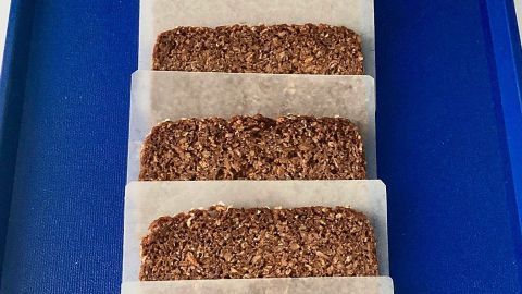 In auf Papier eingewickeltes Brot liegt ordentlich auf einem blauen Tablett, bereit zum Einfrieren.