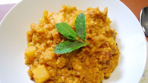 Ein cremiges Rote-Linsen-Curry mit Kokosmilch, serviert in einer weißen Schüssel, garniert mit frischen Minzblättern.