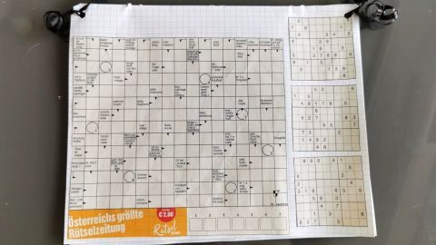 Ein Rätselheft liegt auf einem Tisch, es zeigt ein ausgefülltes Rätsel und Zahlen in Kästchen.