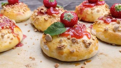 Saftige Erdbeer-Teilchen liegen verführerisch auf einem Holzbrett, dekoriert mit frischen Erdbeeren und Minze.