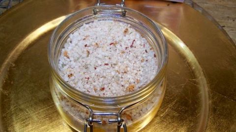 Ein Glas mit Chili-Salz steht auf einem goldenen Teller und strahlt appetitliche Würze aus.